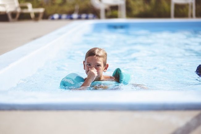 A closeup focus shot of a cute young boy swimming in the pool